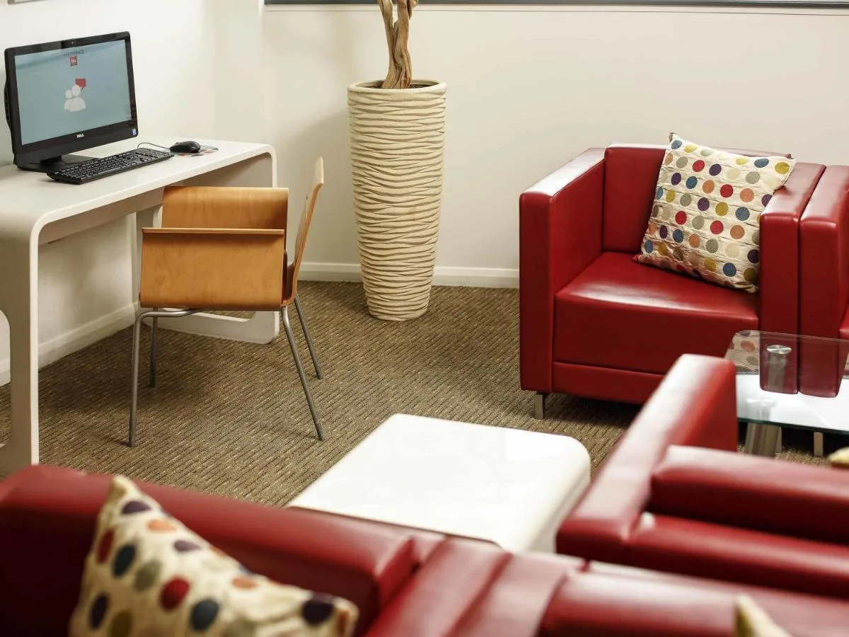 a living room with a red chair and a desk with a computer at ibis Aberdeen Centre – Quayside in Aberdeen